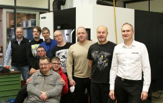 Moderne Technik hält in der HPZ-Werkstatt Einzug: Leiter Josef Albang (l.), Fertigungsleiter Manuell Müllner (3. v. r.), DMG MORI-Vertriebsingenieur Markus Aumann (r.) und die Werkstatt-Beschäftigten freuen sich auf den Einsatz der neuen Fräsmaschine.
