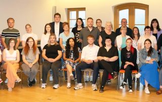 Stellv. HPZ-Vorstandsvorsitzende Brigitte Krause (hinten, 9. v. l.), stellv. Aufsichtsratsvorsitzende Daisy Brenner (hinten, 2. v. l.), JAV-Vorsitzender Felix Beimler (hinten, 8. v. l.), die Betriebsrätinnen Kerstin Hirsch (hinten, 4. v. l.) und Lara Montemayor (hinten, 7. v. r.) sowie Ausbildungsleiterin Tina Beer (hinten, 5. v. r.) ehrten am Montagvormittag im Museumscafé Flossenbürg im Beisein der Abteilungsleiter die Auszubildenden, die 2025 erfolgreich ihren Abschluss absolviert hatten, und deren Mentoren.