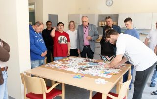 Zum Abschluss des „autism awareness months“ fügten zwei Betreute aus den Autismus-Gruppen die von den HPZ-Mitarbeitern gestalteten Puzzle-Teile zu einem großen Bild zusammengefügt (v. l.): Thomas Fritsch, Ingo Kraus, Dieter Wettinger, Susanne Sindersberger, Bezirkstags-Vizepräsident Lothar Höher, Max Hohlrüther, Johannes Brandl, Lukas Woldrich und Marina Plakhotnik-Hastler. Foto: St. Landgraf